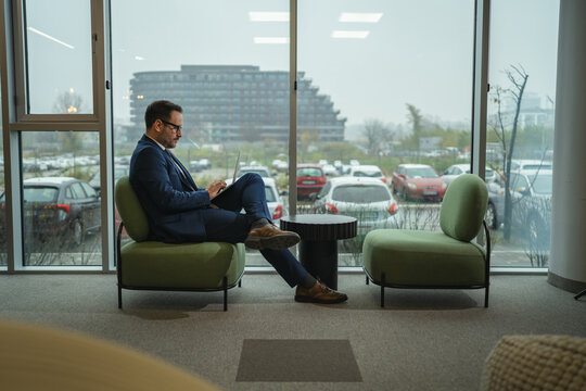 Businessman working on laptop in modern office lounge area