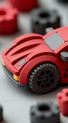 Fototapeta premium A close-up shot of a red toy car with black wheels, surrounded by other toy parts, on a white surface. The image is a studio shot with a shallow depth of field.