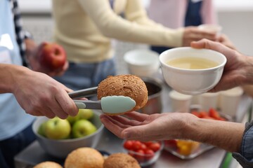 Volunteers giving food to homeless people in shelter, closeup