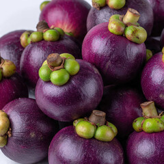 Fresh mangosteens piled naturally, showcasing round shapes, green tops, and deep purple tones. Great for healthy lifestyle themes, fruit packaging, and culinary visuals.