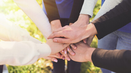 Fototapeta na wymiar Group of volunteers stacking hands outdoors on sunny day, closeup. Banner design