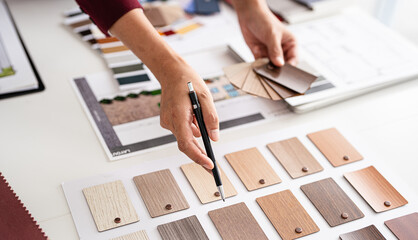 close up hand of Professional interior designer working in the office, asian female architect working on business of Real estateproject , sketching on a house plan choosing swatches and material. © Fahng