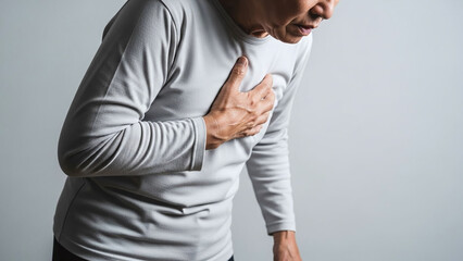 Senior adult holding their chest with one hand slight forward lean showing breathing difficulty medical style