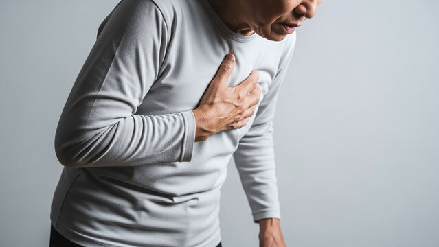 Senior adult holding their chest with one hand slight forward lean showing breathing difficulty medical style