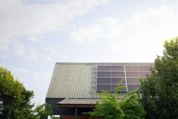 Simple modern house equipped with smart technology uses long solar panels installed on roof to convert natural sunlight into electricity, reducing energy costs, lowering power consumption.