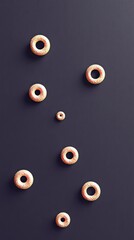 Top-down view of several donut-shaped objects with a textured surface, arranged on a dark background. Studio lighting creates shadows.