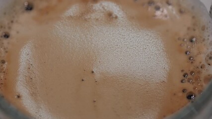 Rich, foamy coffee in a clear glass cup