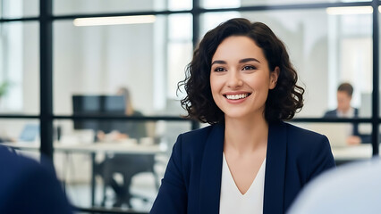 Confident young businesswoman smiling warmly during an important meeting or successful job interview in a modern corporate office setting