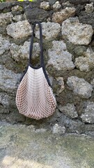 Eco-Friendly String Bag Suspended on Ancient Mossy Stone Wall