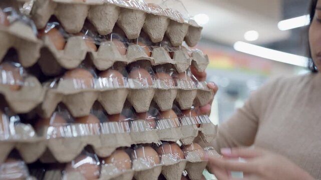 Close-up of a pregnant woman selecting trays of fresh eggs at a grocery store, highlighting healthy food choices for pregnancy nutrition.