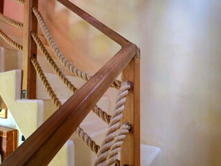 A rustic staircase with a rope handrail, creating a natural and minimalist interior design look. Perfect for themes of craftsmanship, architecture, and decor.