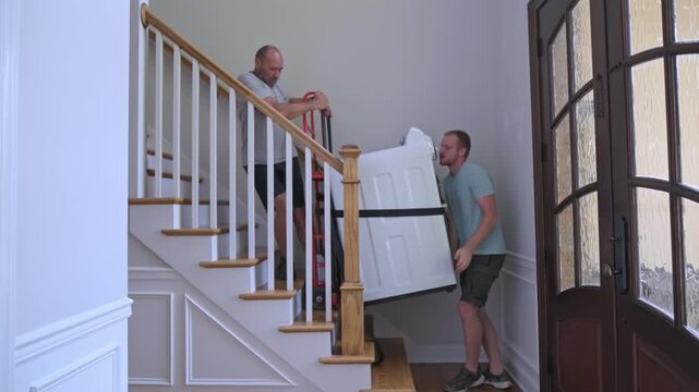 friends elevate heavy washing machine together, community members cooperate to transport large washing device, nearby neighbors and friends work collectively to move cumbersome laundry equipment