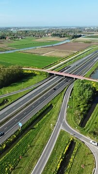 drone captures highway layout, aerial shot of transportation network, elevated view of roads through farmland, unmanned aerial footage showcasing intersection and surrounding fields