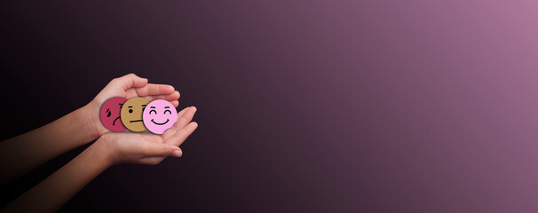 Hands holding three emotion face symbols sad, neutral, and happy on dark background representing mental health awareness, mood change, emotional balance, and psychological wellbeing,