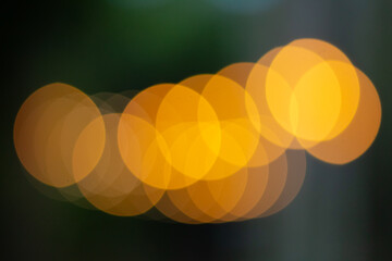 Abstract row of warm golden orange bokeh circles against dark green background
