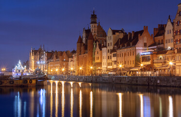 Fototapeta premium Historic waterfront houses and illuminated church towers in the old town of Gdansk Poland at night