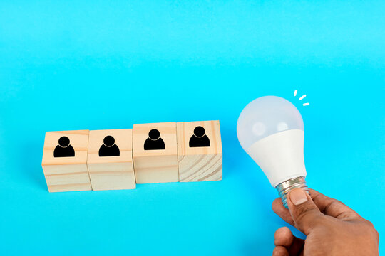 A leadership inspiration concept showing a hand presenting an idea symbol to guide individuals represented by cubes toward collective progress.