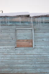 A row of icicles hanging on the corns of a small wooden house