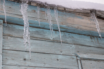 A row of icicles hanging on the corns of a small wooden house