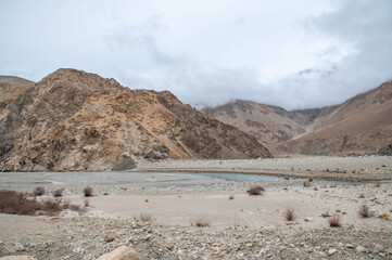 Beautiful mountain landscape in Nubra, Ladakh featuring a dry riverbed running through the center. Rugged Himalayan terrain with serene valleys, textured earth patterns, and stunning natural beauty