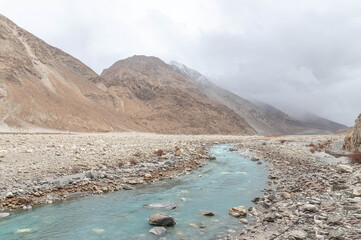Turquoise blue river winding through the Himalayas, creating beautiful painterly curves. Stunning mountain landscape with vibrant water tones, natural beauty, and serene scenic flow like a painting