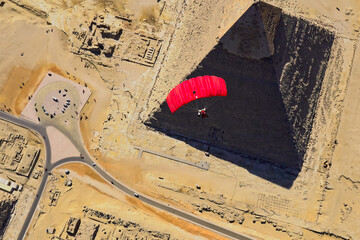 Red Parachute next to the pyramids of Egypt from above © Yannis
