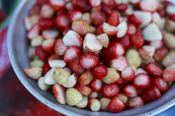 Close up metal bowl, fresh cut strawberry fruit. Healthy sweet red berry pile, appetizing, juicy, natural food background for summer dessert, diet, nutrition concept