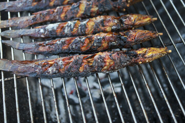 Close up of savory grilled catfish cooking on charcoal barbecue. This fresh seafood meal, traditional outdoor dish, shows delicious charred fish on hot metal grate
