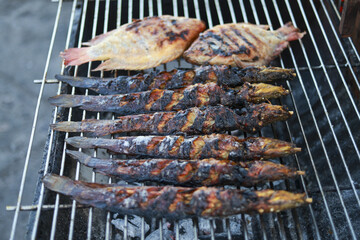 Appetizing grilled catfish and tilapia fish on barbecue. fresh seafood meal perfect for summer cookout. Traditional food cooking on hot charcoal grill outdoors