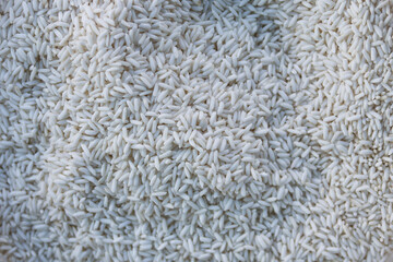 Close up top view of pile of raw uncooked white rice grain. This natural food background shows healthy carbohydrate staple ingredient for cooking Asian cuisine