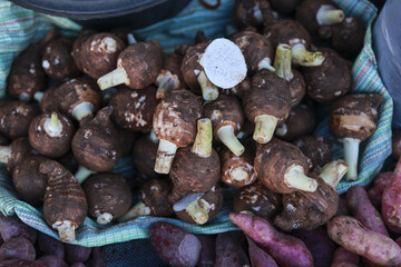 Fresh pile of brown taro root vegetable at market. This healthy organic produce, staple food, sits ready for sale, showcasing natural agricultural abundance