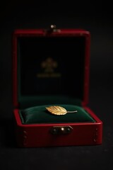 Elegant gold feather brooch displayed in a luxurious red velvet jewelry box