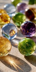 Close up view of various colorful translucent glass gazing balls resting on a textured stone surface