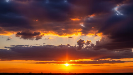 Obraz premium Vibrant sunset illuminating the sky with dramatic clouds casting a warm glow over a vast landscape