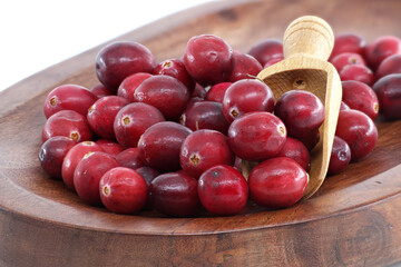 Fresh cranberries in a wooden bowl with a wooden scoop, ready for cooking