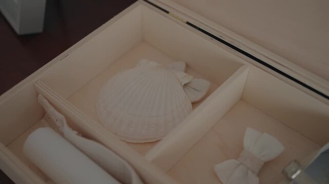 white shell and fabric bows arranged neatly inside a wooden keepsake box
