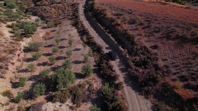 Aerial shot of black car driving through a dirt road on the Tabernas desert, Almeria, Spain