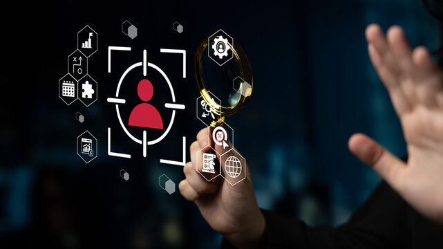 A modern business concept showcasing a hand holding a magnifying glass over a user profile surrounded by technology icons, emphasizing digital innovation and focused analysis. Gantry