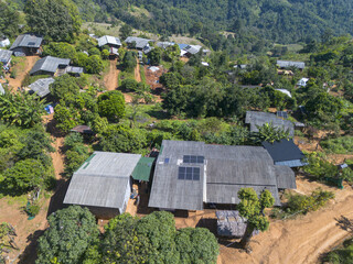 Aerial view of remote rural village with solar panel on house roof. peaceful scene of sustainable energy and off grid community living in green mountain landscape © CoreRock