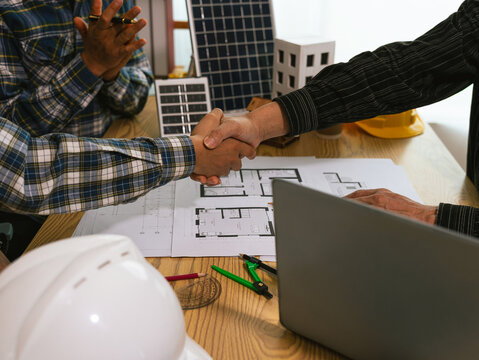 Partner and contractor concept of construction team shaking hands greeting new project start plan, project contract in office center at construction site.