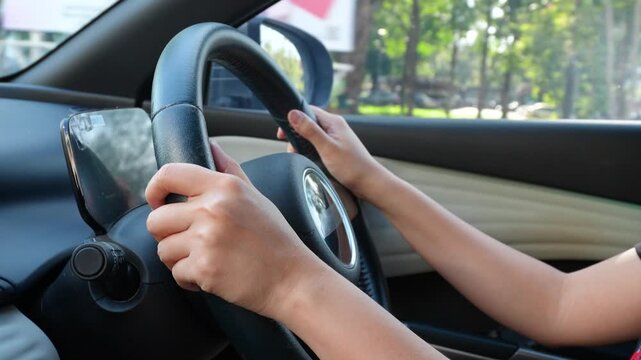 Action of a driver is gripping on steering wheel to control the car during driving. Transportation mode with close-up and selective focus on the hand.	