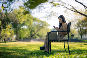 Woman working remotely with laptop and smartphone in park
