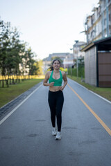 Fototapeta premium Asian woman running on a road, exercising for health and wellness