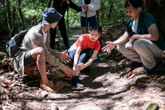 Hikers helping injured friend with sprained ankle in forest
