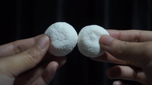 Hands Gently Squeeze Two Soft White Candy Balls