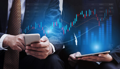 Business professionals engaged in financial analysis using smartphones and tablets, surrounded by graphs, illustrating modern technology role in investment strategies. Scalp
