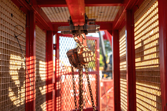 Metal pulley and hoist chain box, manual equipment using the lifting heavy object, it install on the beam of mobile toolbox. Industrial equipment object, close-up.