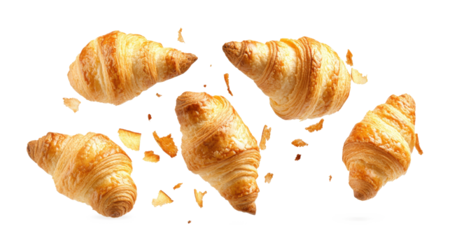 A close-up of a few croissants with crumbs flying out of them