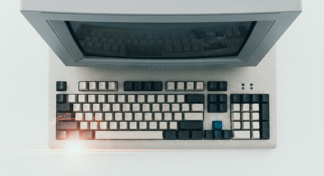 An overhead shot captures an old computer, the screen tilted and keyboard detailed, showcasing technological history.