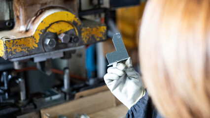 Worker Inspecting Metal Stamped Part in Factory Workshop